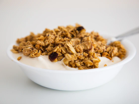 Mangkuk putih berisi yoghurt dengan taburan granola